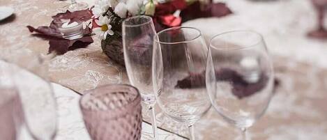 A table set with gold and silverware, clear glasses, and a decorative centerpiece.