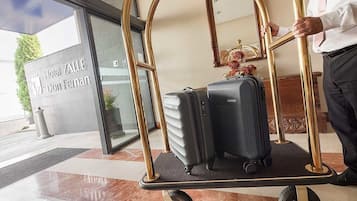 Entrada de um hotel com um carrinho de bagagem, uma placa indicando