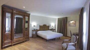 Une chambre d’hôtel avec un grand lit, une armoire en bois, un bureau avec une chaise et un miroir.
