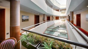 Un intérieur d’hôtel moderne avec un couloir à plancher de verre, des lambris en bois et une vue sur le ciel à travers le plafond.