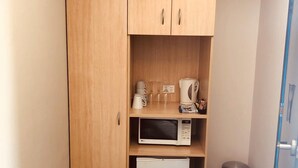 Eine kompakte Küchenzeile mit Mikrowelle, Kaffeemaschine und kleinem Kühlschrank.