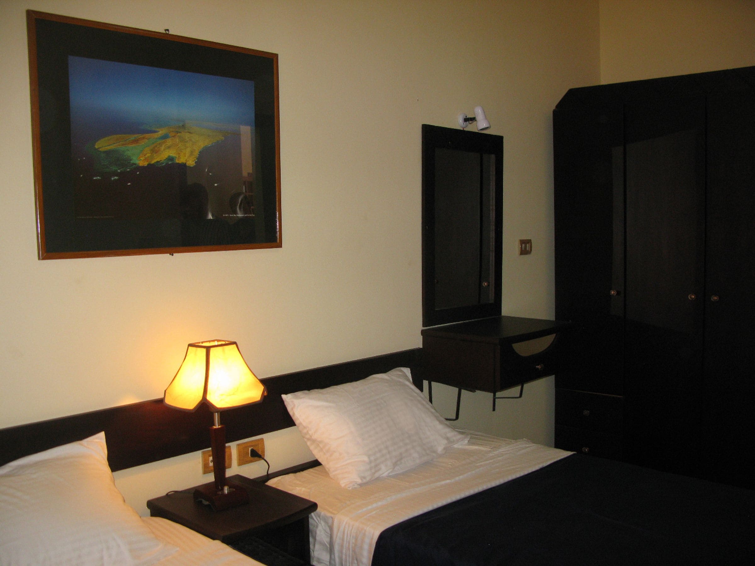 Une chambre d’hôtel avec deux lits, un bureau, une télévision et une armoire.