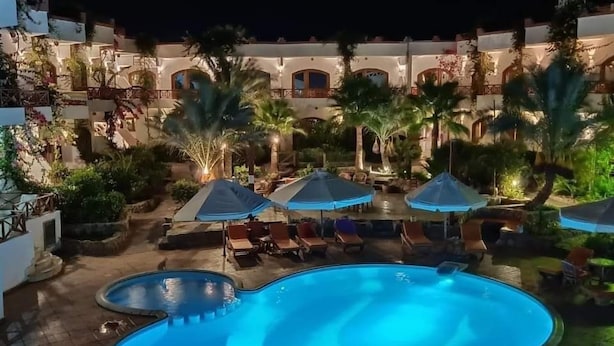 A nighttime view of a resort with a swimming pool, lounge chairs, and umbrellas. - Red Sea Relax (Dahab)