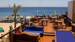 A wooden deck with tables and chairs overlooking the sea. - Red Sea Relax (Dahab)