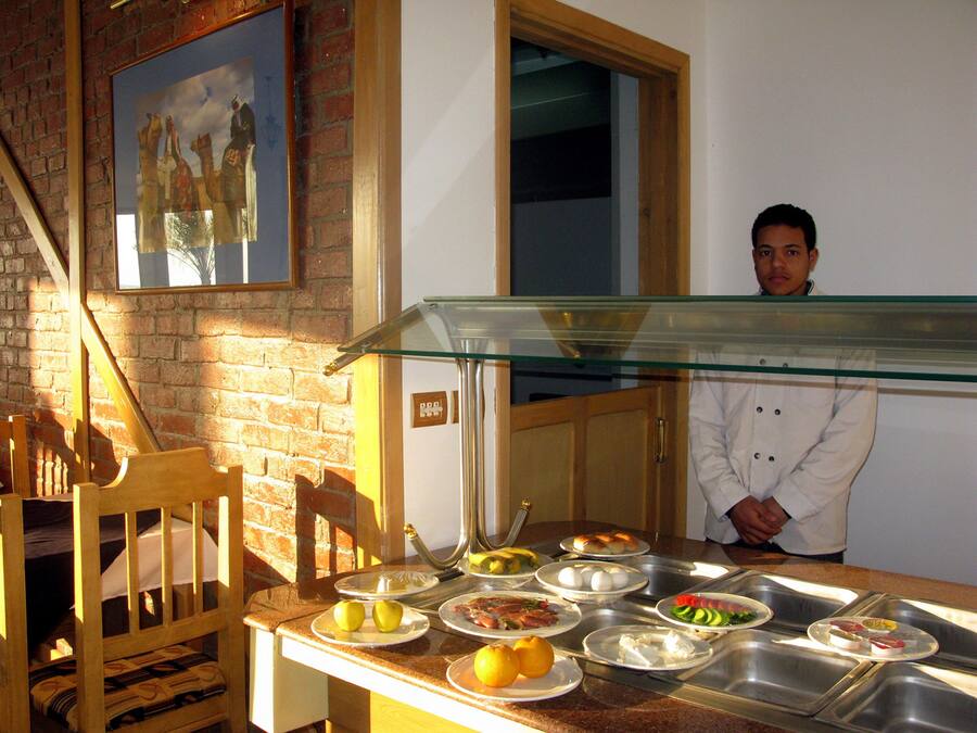 Un buffet proposant divers plats, avec une personne debout derrière une paroi de verre.
