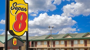 Ein Super 8 Hotel mit auffälliger Beschilderung, ein zweistöckiges Gebäude und ein klarer, blauer Himmel mit Wolken.