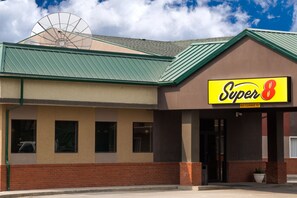 Um motel Super 8 com telhado verde, paredes bege e base de tijolos.