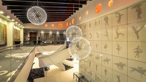 Un vestíbulo moderno con barandilla de vidrio, una escalera central y lámparas esféricas decorativas.