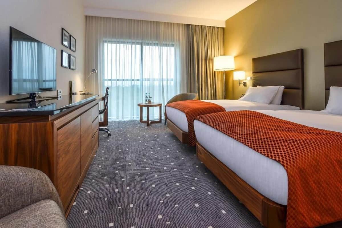 A hotel room with a bed, a desk, a TV, and a chair.