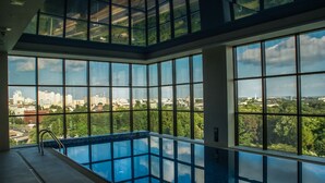 Piscina interior moderna con amplios ventanales que ofrecen vistas a la ciudad.