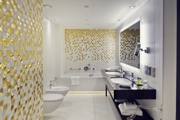A modern bathroom with two sinks, a bathtub, and a large mirror.