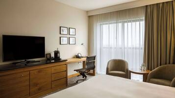 A hotel room with a large bed, a desk with a computer, a television, and a chair.