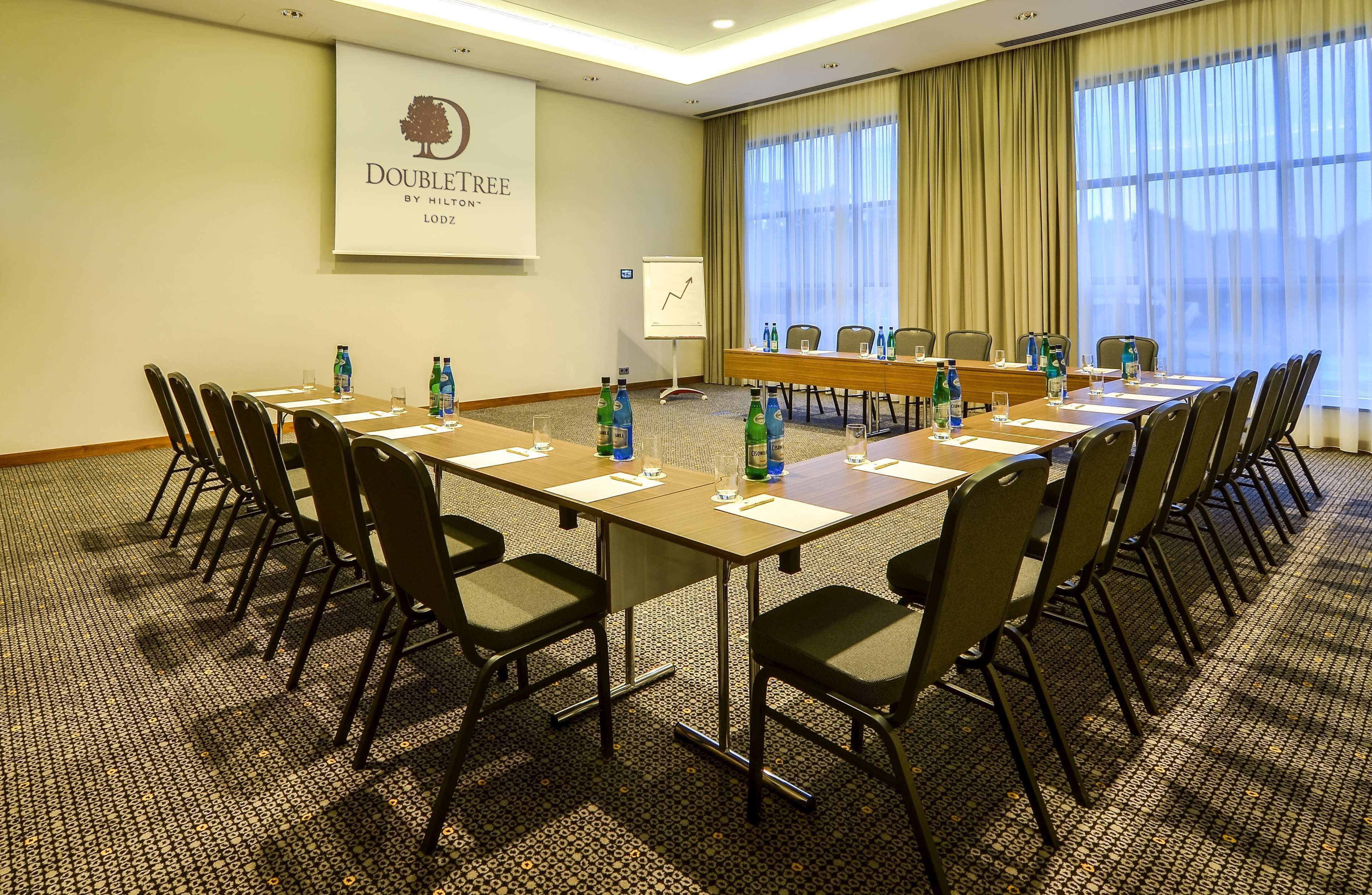 A conference room with a long table, chairs, water bottles, and a presentation screen.