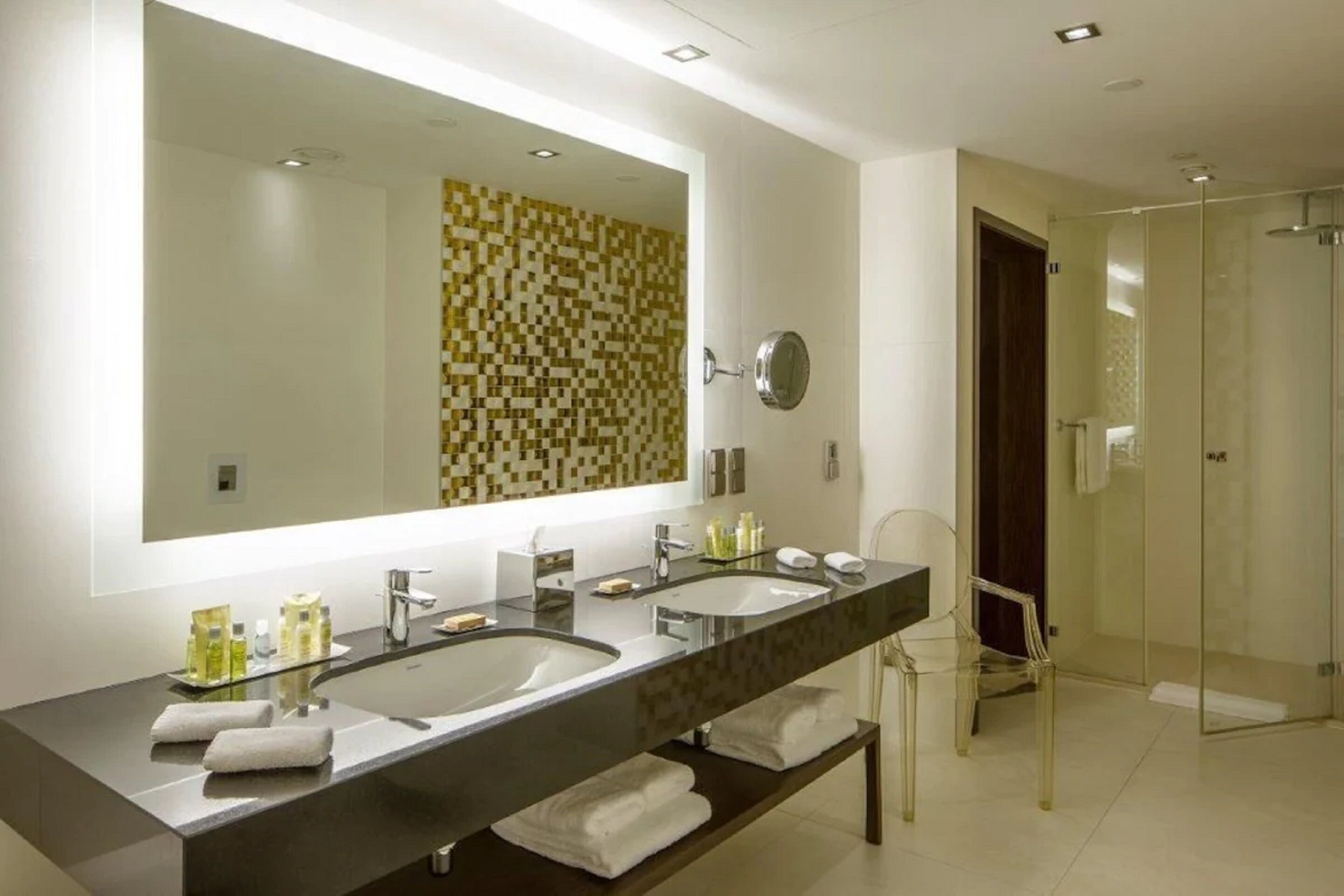 Un baño moderno con dos lavabos, un espejo grande y una cabina de ducha de vidrio.