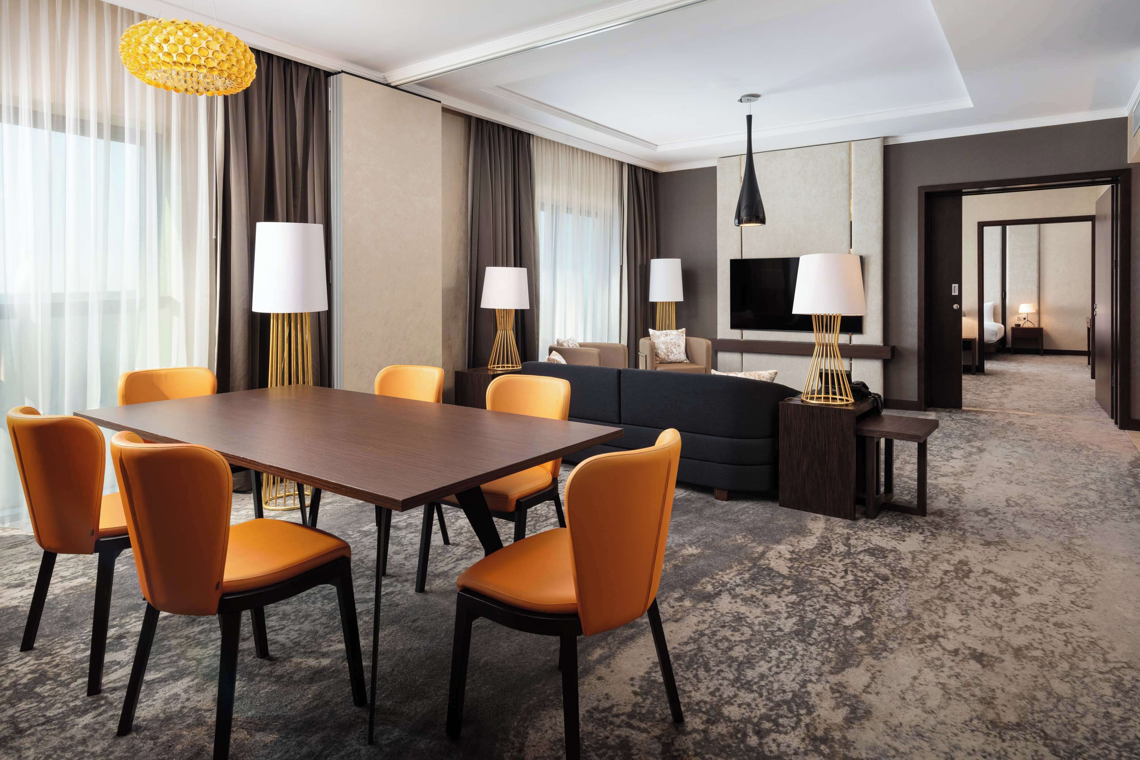 A hotel room with a dining area, a sofa, and a TV.