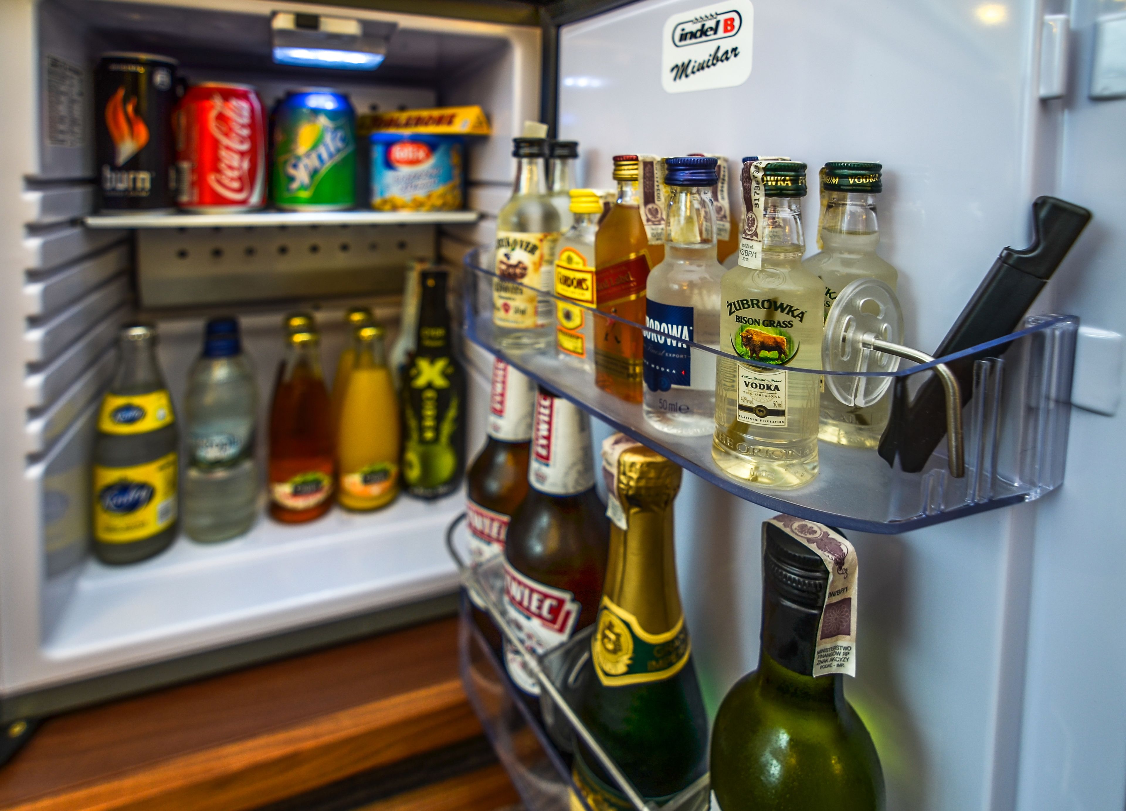 A refrigerator stocked with various beverages including soda, beer, and vodka.