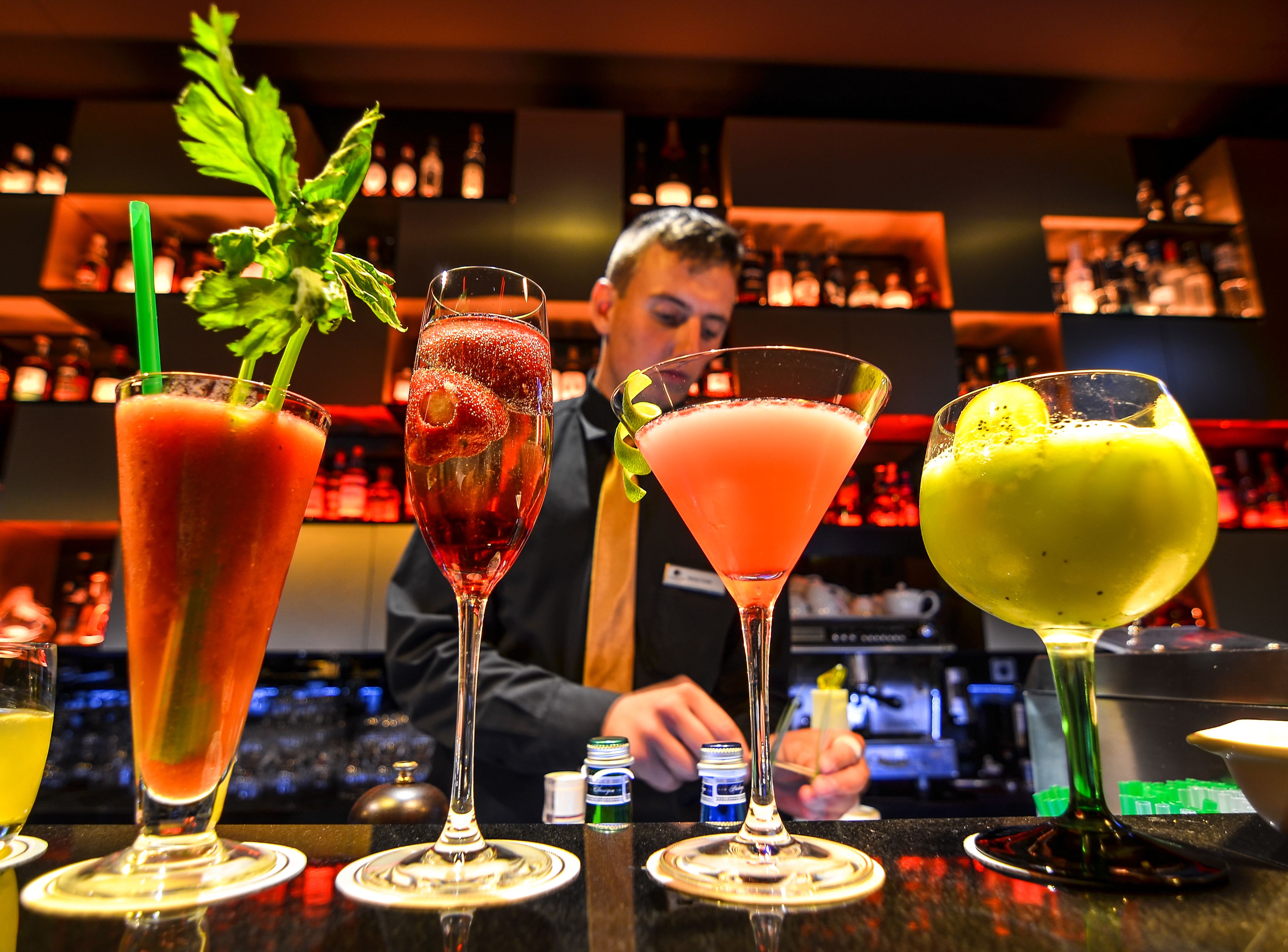 Un bar con cuatro cócteles distintos en la barra.