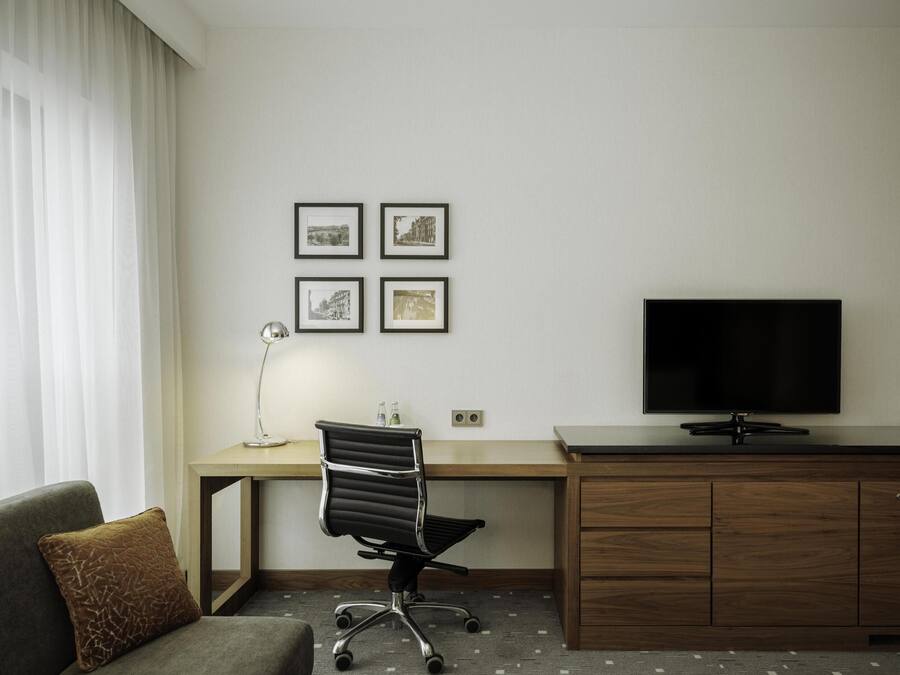 Habitació d'hotel amb escriptori, cadira, televisió i sofà.