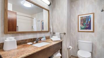 A bathroom with a marble sink, a large mirror, a framed picture on the wall, and a white toilet.