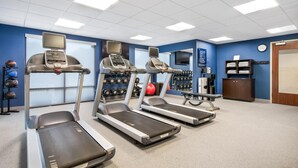 A fitness room with treadmills, a ball, and dumbbells.