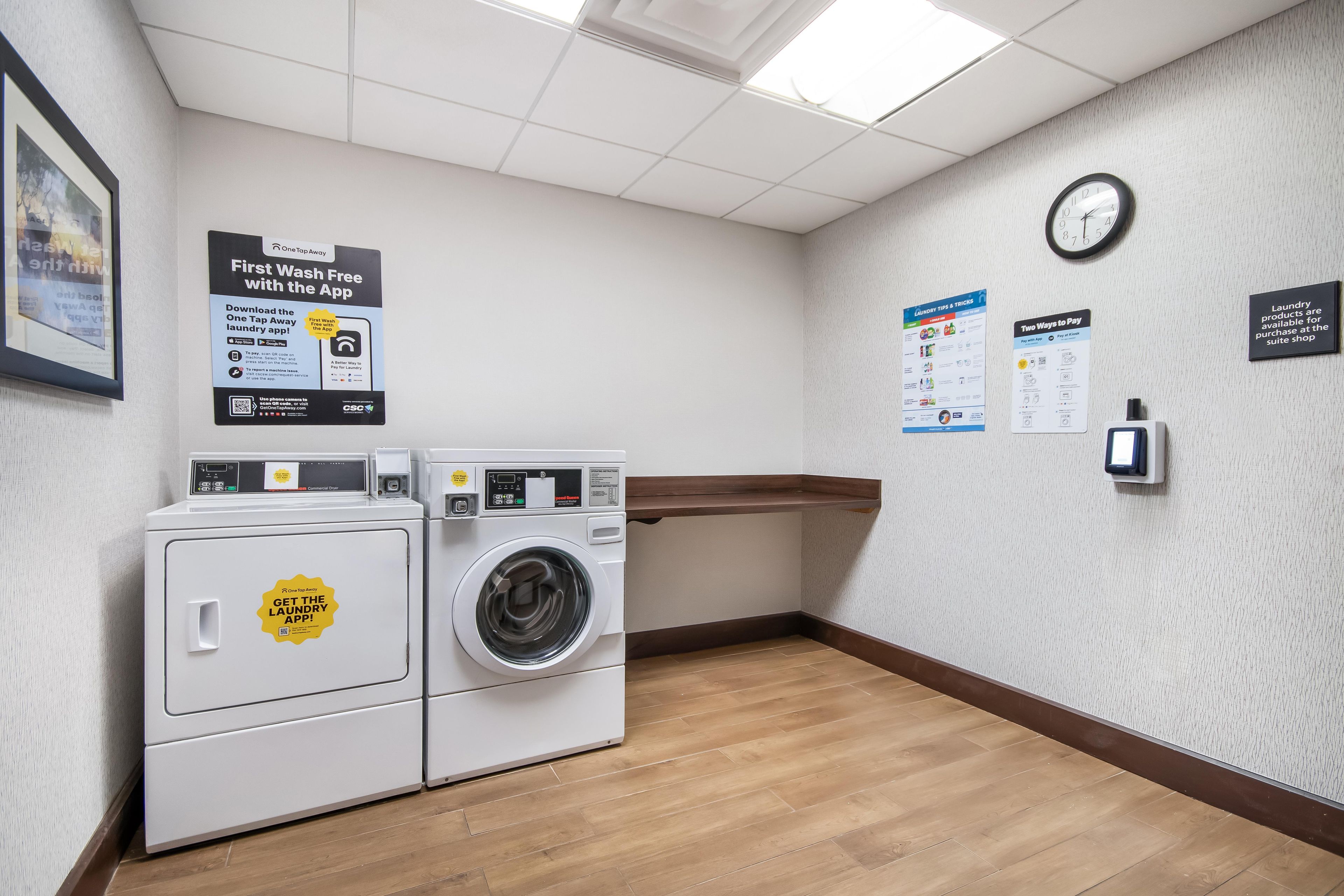 A laundry room with a washing machine, dryer, and a clock on the wall.