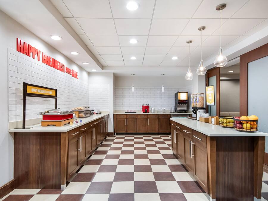 A modern kitchen with a checkered floor, wooden cabinets, and a breakfast bar.