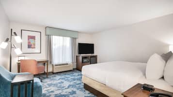 Habitación de hotel con una cama grande, un escritorio con silla, un televisor y un teléfono.