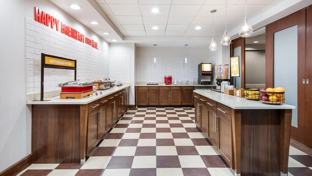 A modern kitchen with a checkered floor, wooden cabinets, and a breakfast bar.
