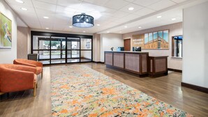 A hotel lobby with a reception desk, seating area, and large windows.