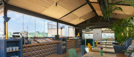 A restaurant with a high ceiling, large windows, and a view of the city.