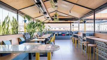 Un restaurante moderno con techos altos, listones de madera y grandes ventanales.