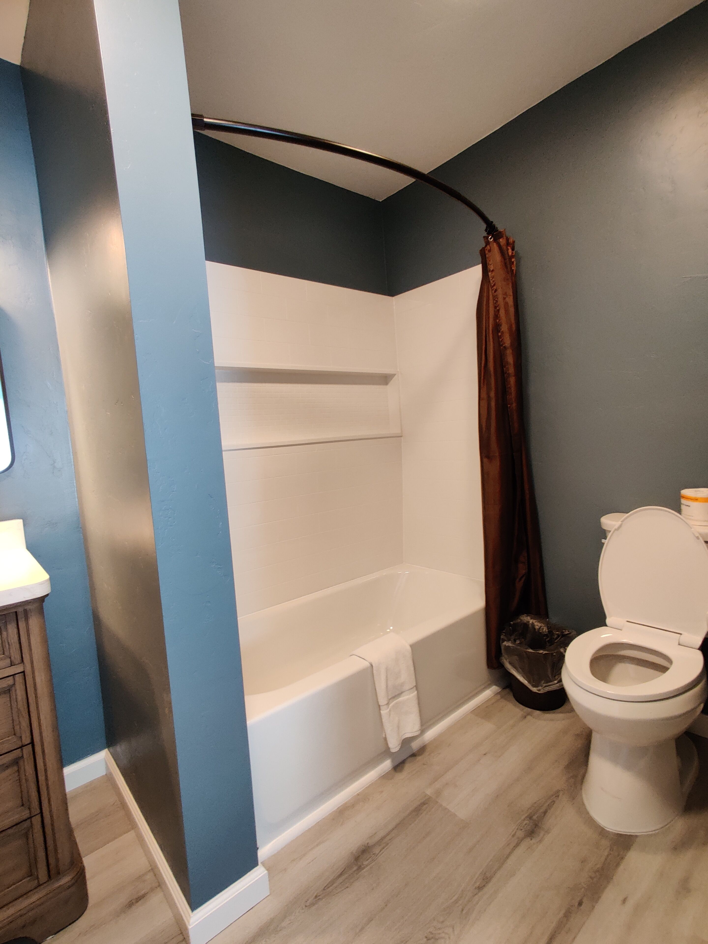 A bathroom with a bathtub, toilet, and wooden cabinet.