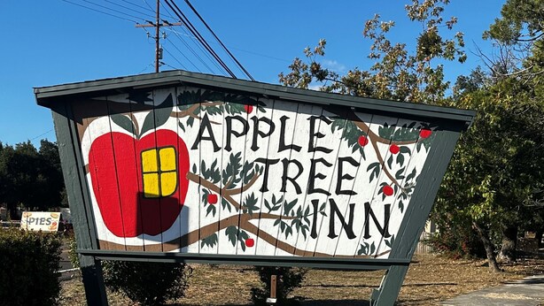 A sign for 'Apple Tree Inn' with a painted apple and tree branches.