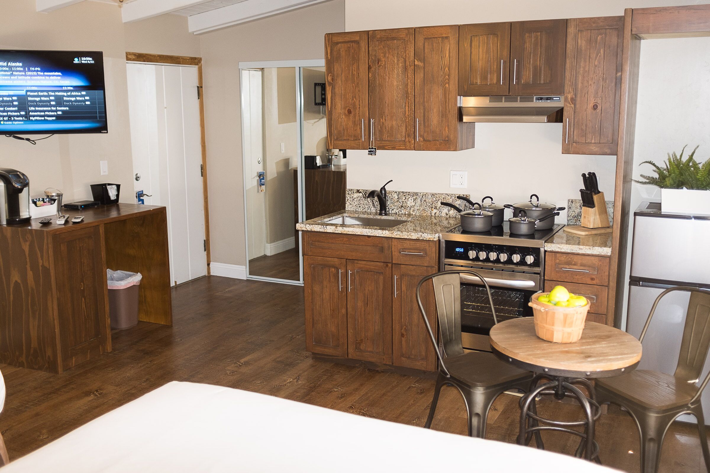 A compact kitchen with wooden cabinets, a built-in oven, and a dining area with a small table and chairs.