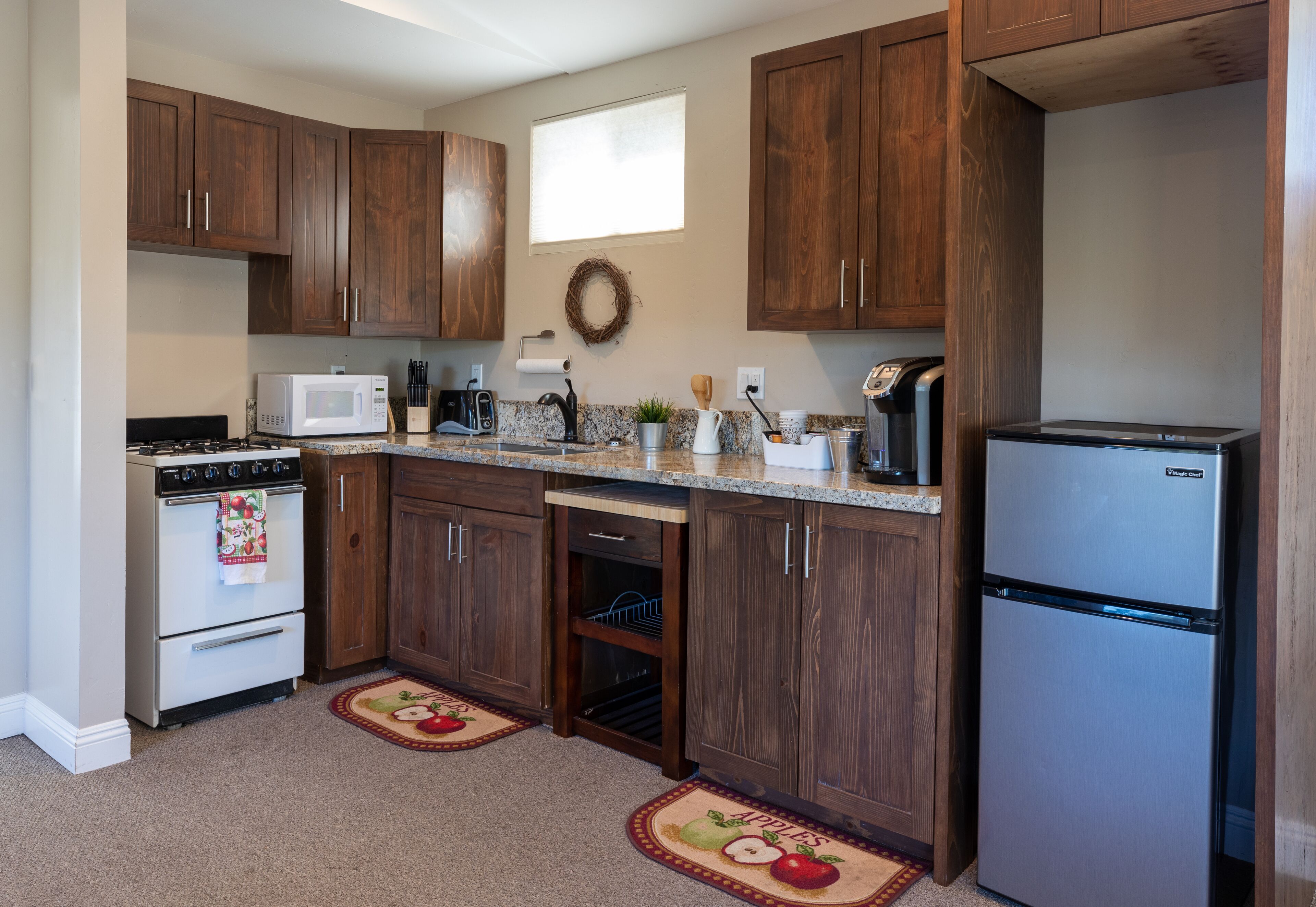 A kitchen with wooden cabinets, a stainless steel refrigerator, a microwave, a stove, and a dishwasher.