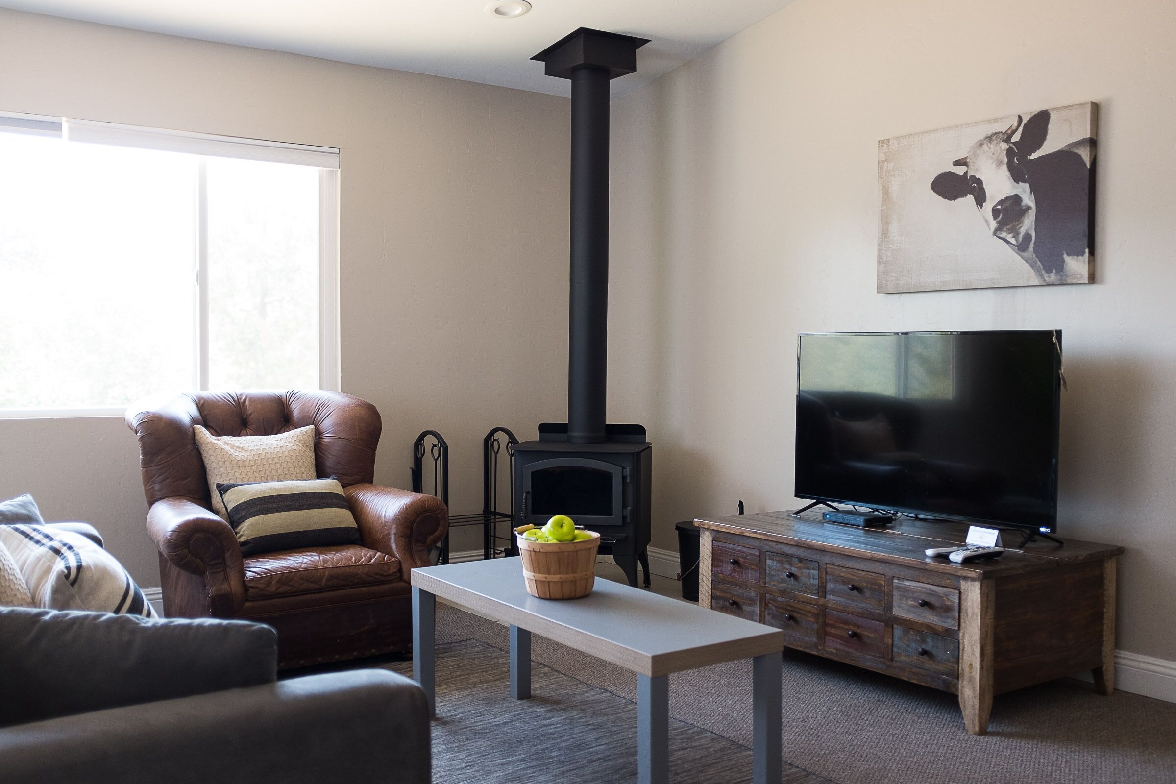 A living room with a leather armchair, a television, a wooden cabinet, and a fireplace.