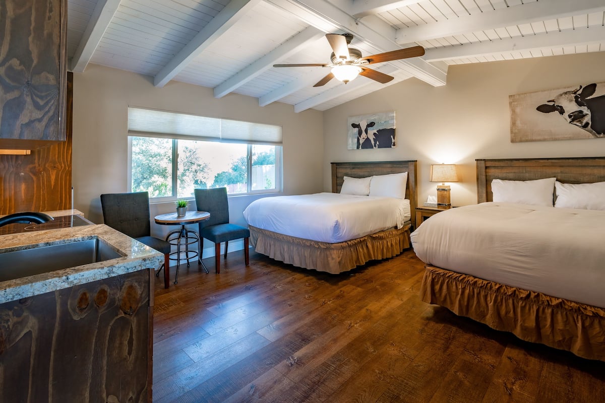 A bedroom with two beds, a ceiling fan, a window, and a desk with a chair.