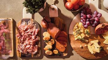 Diversos alimentos como carnes, quesos y frutas dispuestos sobre tablas de madera.
