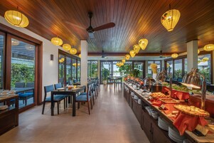 Restaurante com teto de madeira, grandes janelas e uma área de buffet.