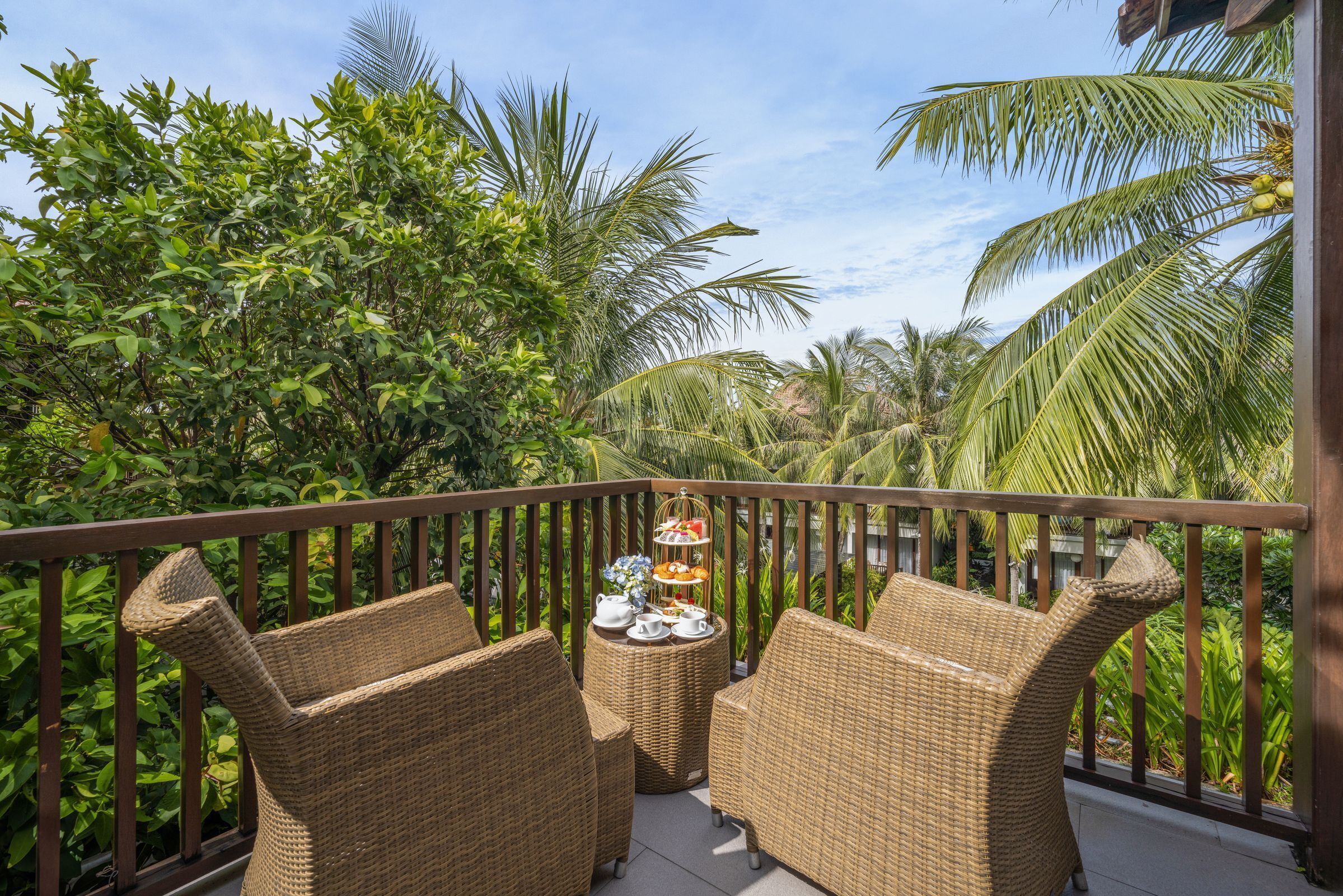 A balcony with wicker furniture and a tiered tray of refreshments.