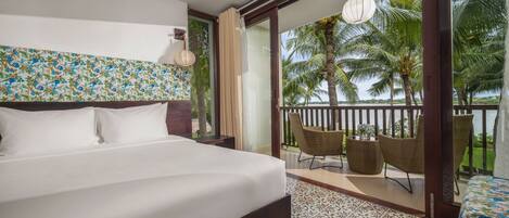 A bedroom with a large bed, a view of palm trees, and a balcony with wicker furniture.