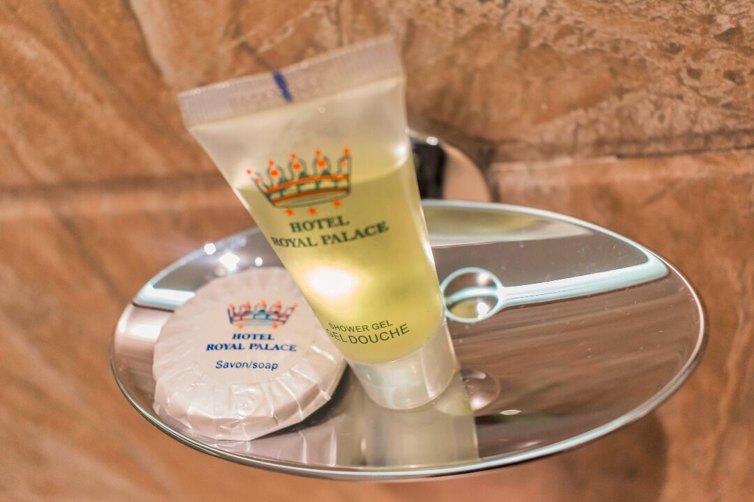 Geles y jabones para ducha y manos, de la marca Hotel Royal Palace, sobre una bandeja reflectante.