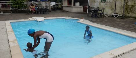 Una piscina con dos niños jugando en el agua.