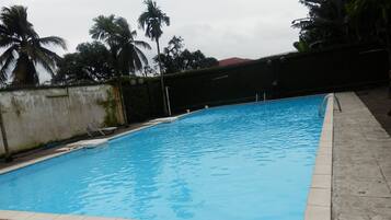 Relax by the serene pool surrounded by lush greenery and palm trees.