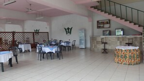 Enjoy meals and social gatherings in this dining area with round tables, individual chairs, and a staircase.