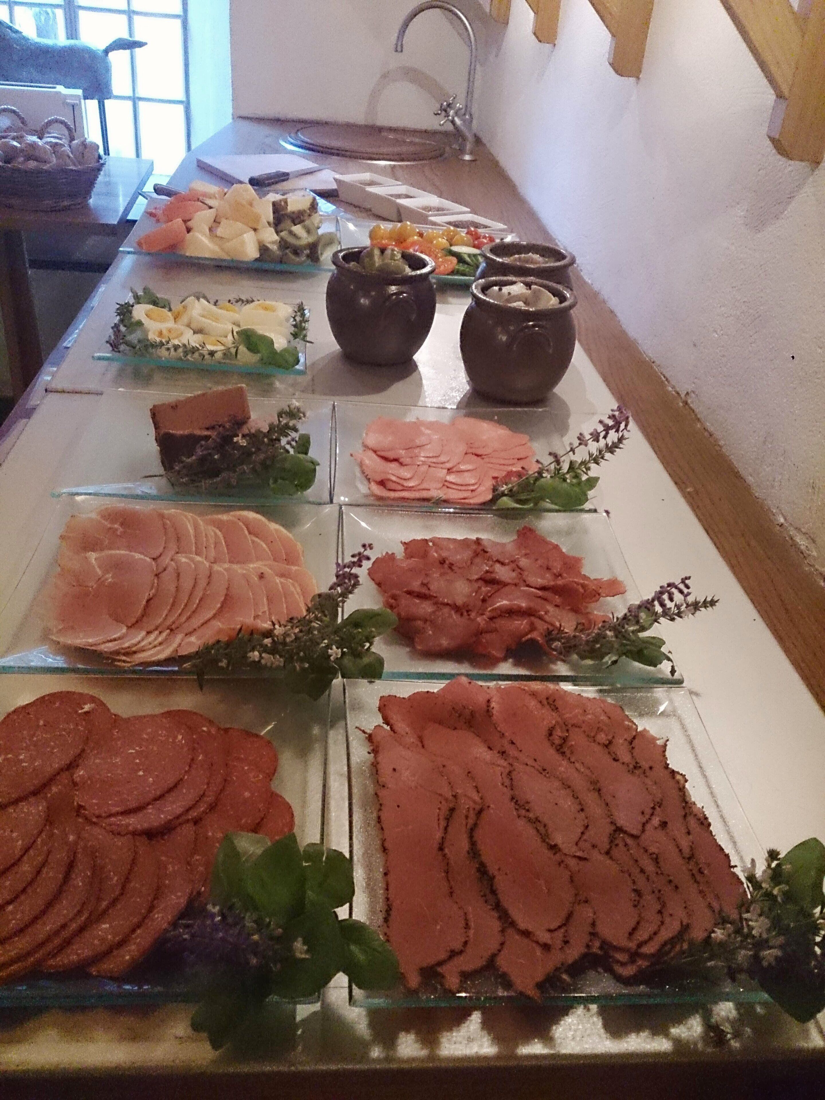 A buffet with various meats and cheeses.