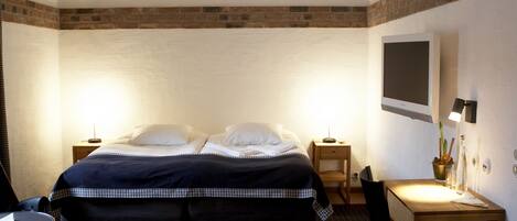 Ein Hotelzimmer mit Bett, Schreibtisch, Stuhl, Fernseher und Lampe.