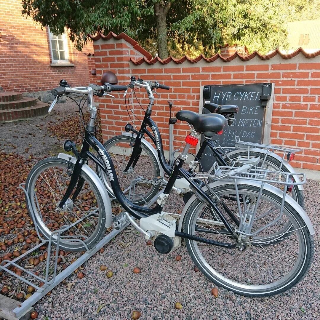 Dos bicicletas estacionadas frente a un edificio de ladrillo con un cartel que dice "HYR CYKEL BIKE METEN DAG".