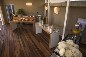 Un bar pour prendre le petit-déjeuner, avec un sol en bois, une plante en pot et un distributeur de jus.