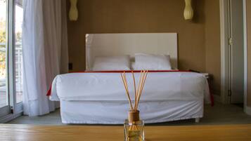 Una habitación de hotel con una cama, una mesa de madera y un difusor de cañas en primer plano.